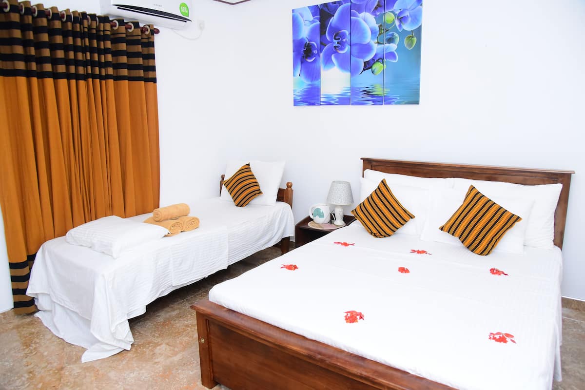 A hotel room with two beds, a large painting of flowers, and a window with curtains.