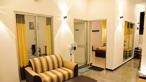 A modern living room with a sofa, a coffee table, and a fan. - White Villa Airport Transit Hotel (Seeduwa - Katunayake)