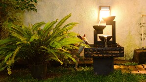 A stone water feature with a basin and a small waterfall, surrounded by lush green ferns and plants. - White Villa Airport Transit Hotel (Seeduwa - Katunayake)