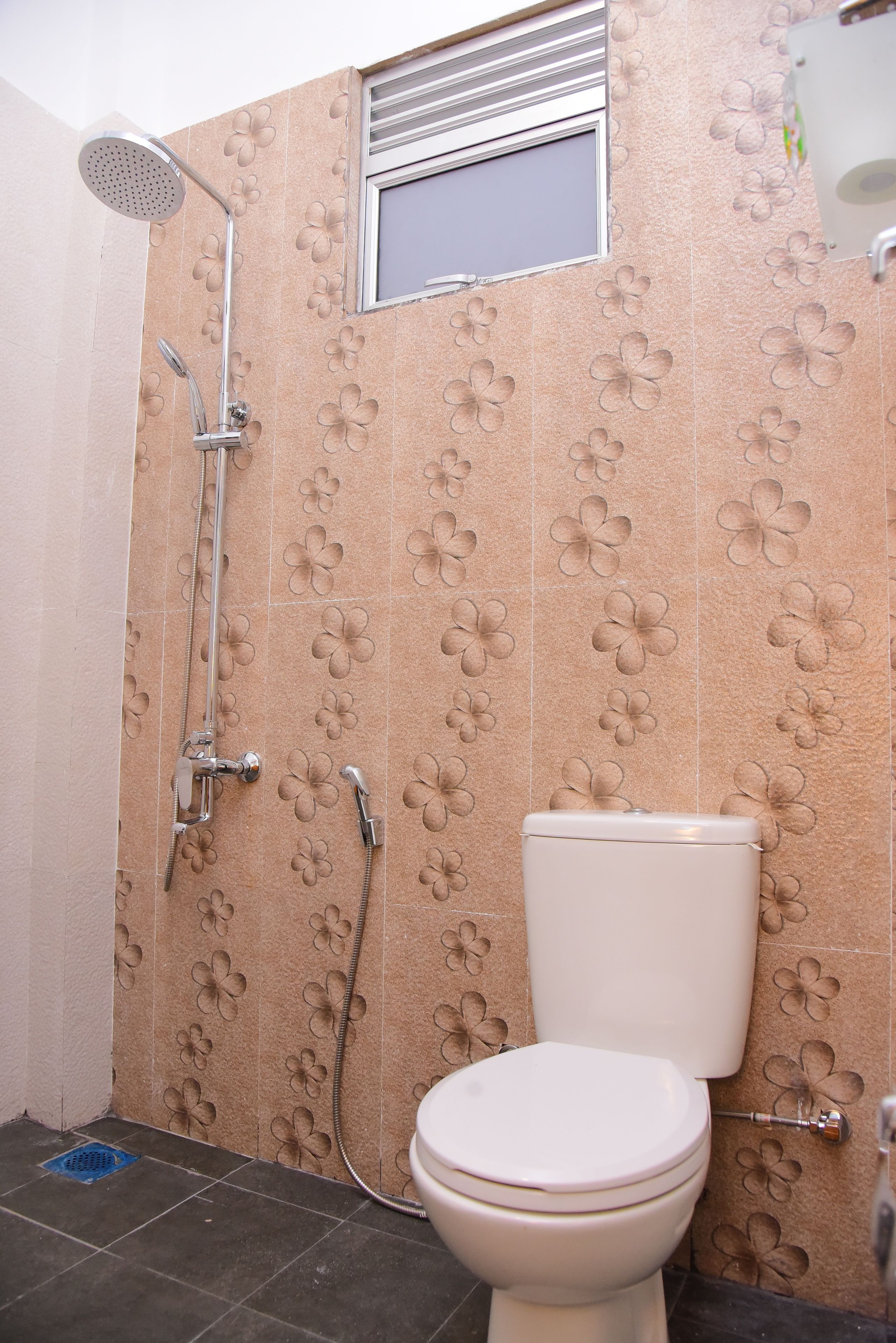 A bathroom with a toilet, a shower, and a window.