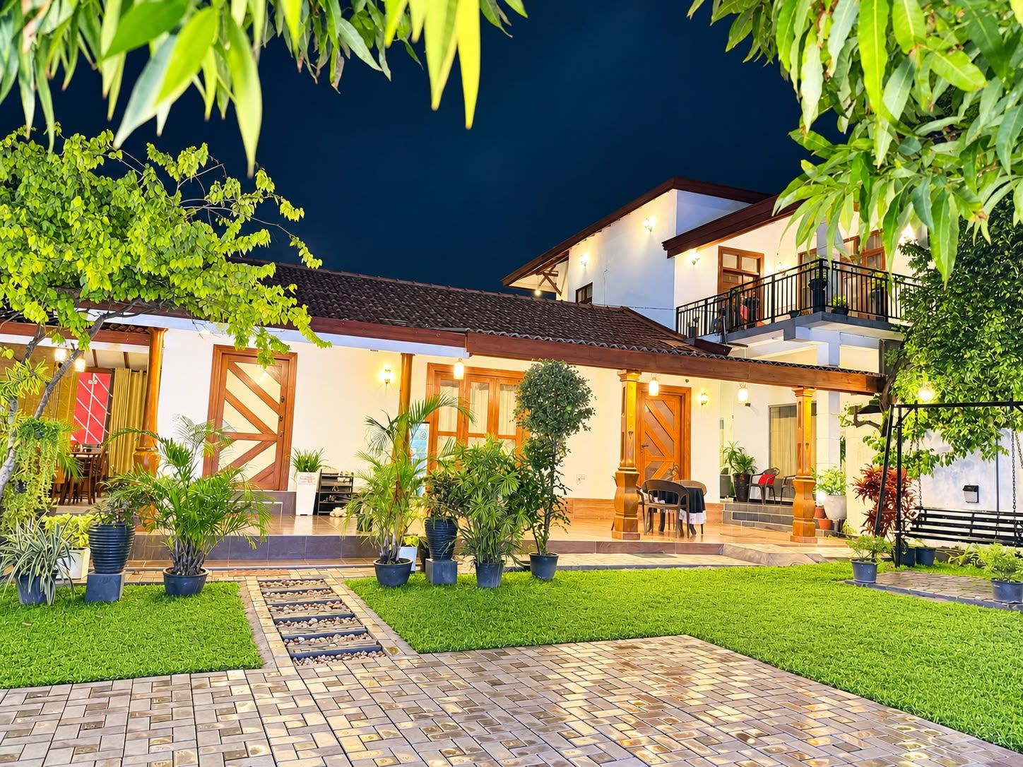 A two-story building with a patio area, potted plants, and a well-maintained lawn.