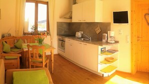 Una cocina compacta con comedor, muebles de madera y un televisor montado en la pared.