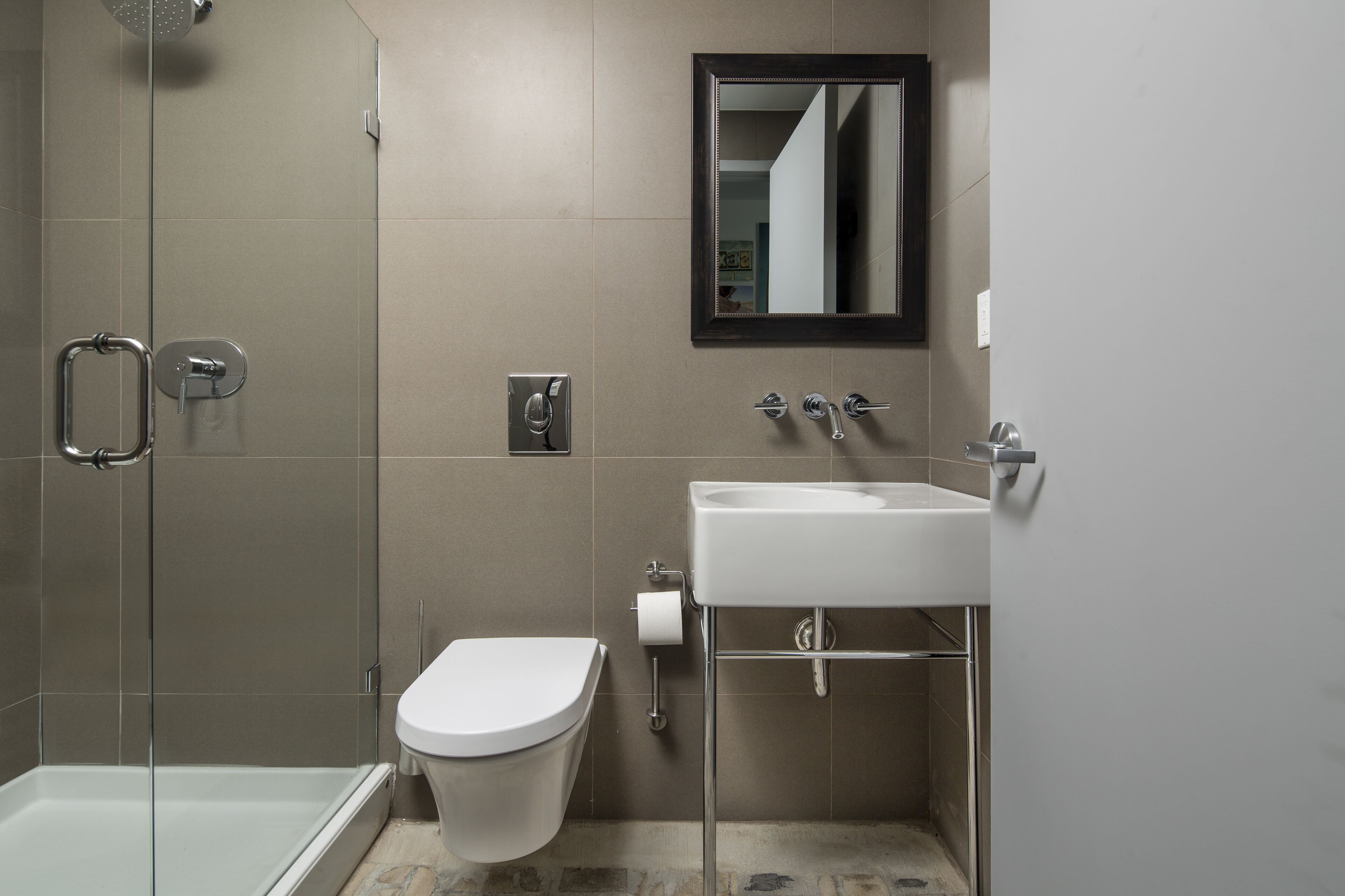 A modern bathroom with a glass shower enclosure, a white toilet, and a sink with a mirror above it.