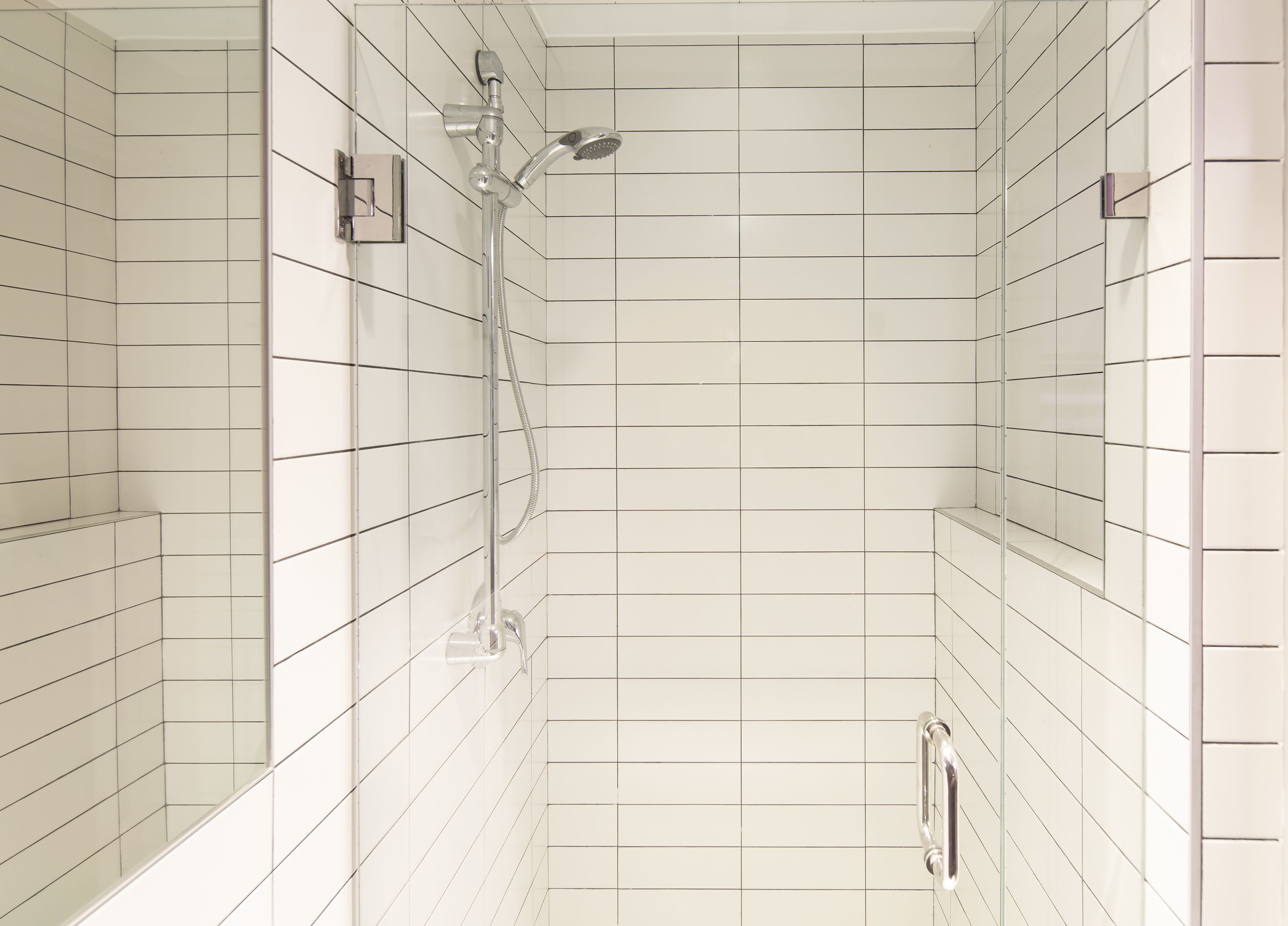 A modern bathroom with white subway tiles, a glass shower enclosure, and a handheld showerhead.