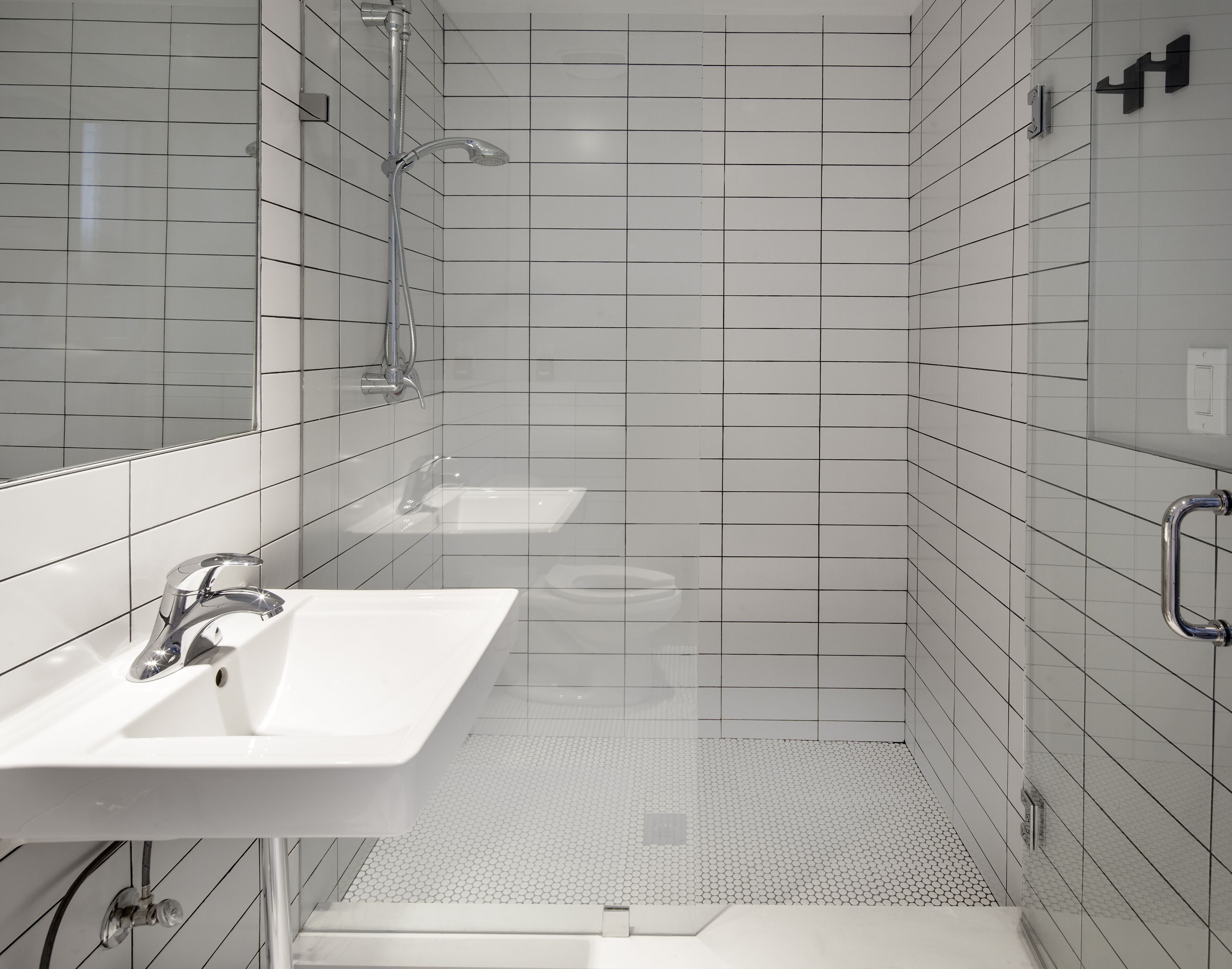 A modern bathroom with a white sink, mirror, and shower.