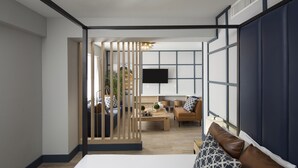 Una habitación de hotel moderna con una cama grande, un panel de madera, un sofá, una mesita de café y un televisor montado en la pared.