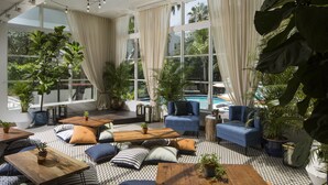 Un área de estar moderna con diversas opciones de asientos, ventanas amplias y plantas de interior.