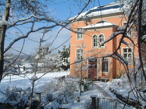 A two-story building with a red door and white windows, surrounded by snow-covered trees and a clear sky. - Spacious vacation apartment on the Elbe slope - directly on the Blue Wonder (Dresden)