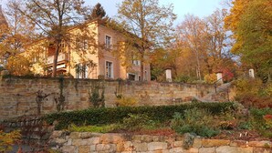 Eine Steinsäule mit einem Garten vor einem Gebäude mit mehreren Fenstern und einem Balkon.