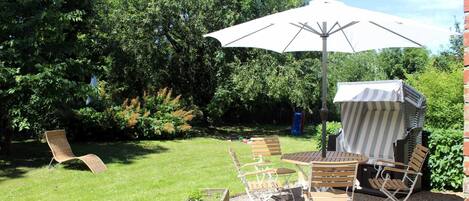 An outdoor patio with a table and chairs, a large umbrella, and a wooden bench.