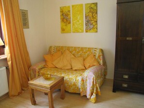 A living room with a sofa, a small wooden table with a bowl, and a cabinet. - Vacation apartment Altstadtoase - Ferienw. Old Town Oasis | App: Tillyschanzenblick | (Hann. Münden)