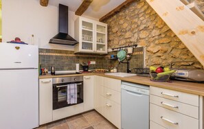 Una cocina con pared de piedra, horno empotrado y escurreplatos.