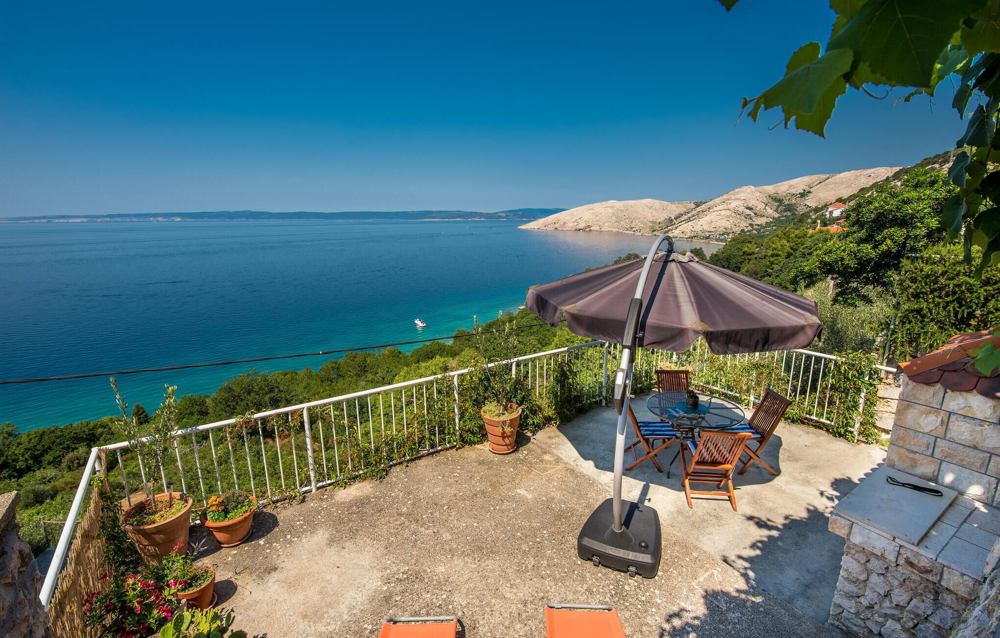 Un patio con mesa y sillas, una parrilla y vista al mar.