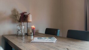 Une table en bois sur laquelle se trouvent un vase contenant des plantes séchées, une bougie et un magazine.