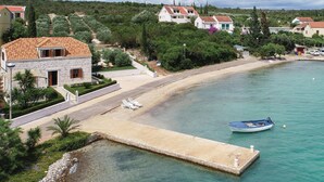 A coastal area with a clear view of a beach, a boat docked at the pier, and residential buildings in the background.