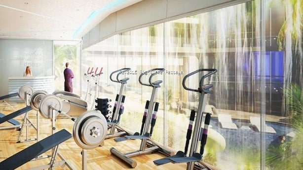 Ein modernes Fitnessstudio mit Laufbändern, Kraftgeräten und einem großen Fenster mit Blick auf Grünflächen.