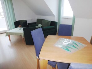 Una stanza con un tavolo da pranzo, un divano verde e una sedia blu.
