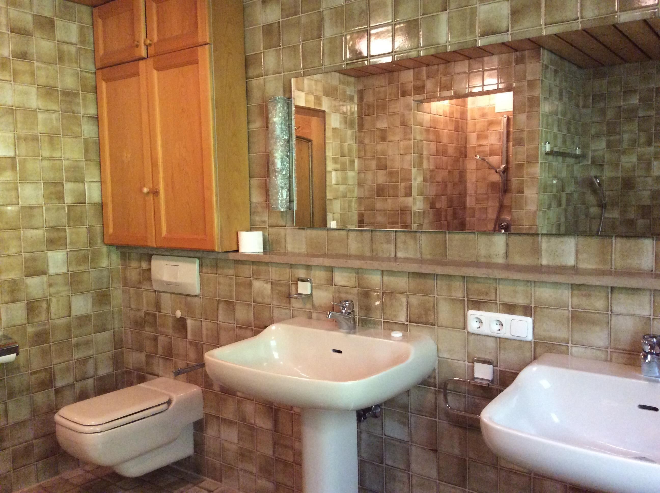 A bathroom with two sinks, a toilet, and a mirror.