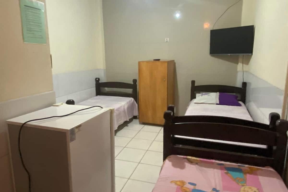A bedroom with two single beds, a desk, a wardrobe, and a ceiling fan.