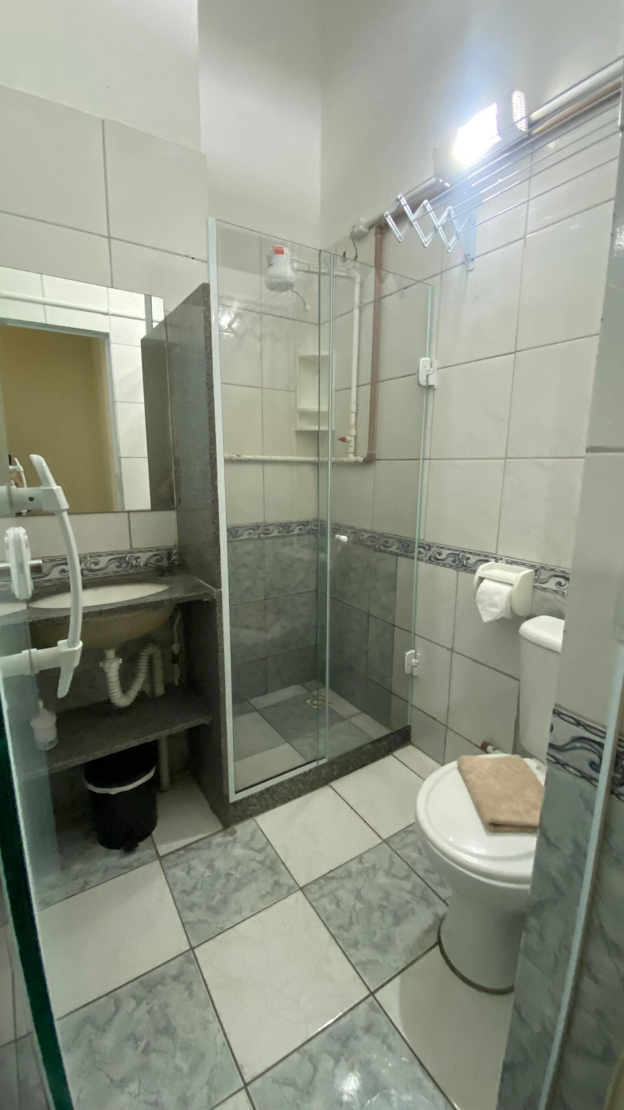 A bathroom with a glass-enclosed shower, a toilet, and a sink with a mirror above it.