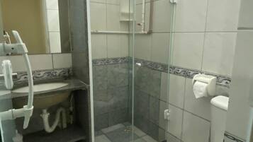 A bathroom with a glass-enclosed shower, a toilet, and a sink with a mirror above it.