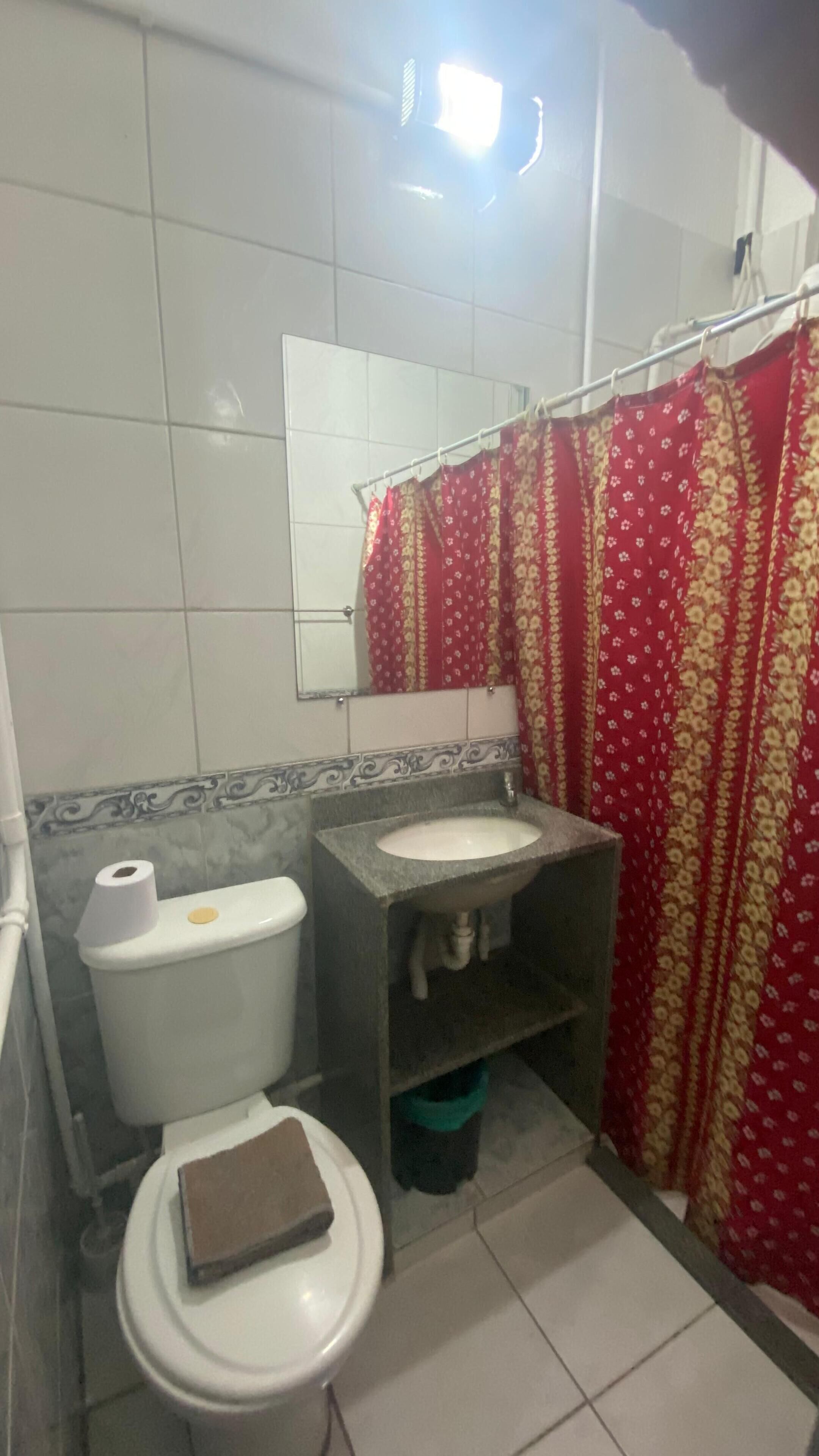 Un baño con inodoro, lavamanos y cortina de ducha.