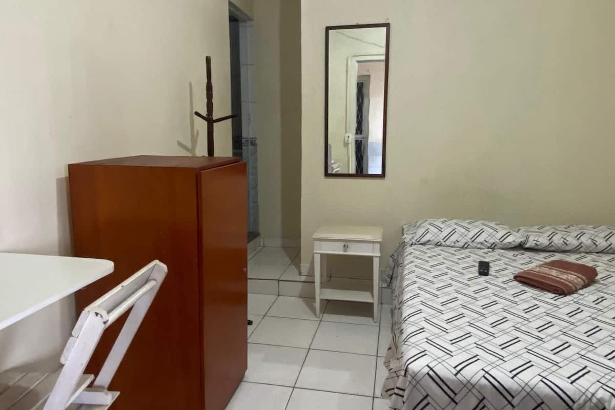 A small, clean room with a bed, a desk, and a wardrobe.