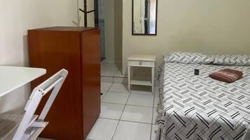 A small, clean room with a bed, a desk, and a wardrobe.