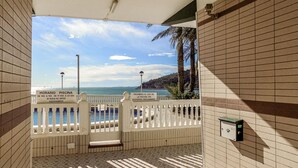 Zona de piscina con vistas al mar, cerca una valla blanca y un cartel con los horarios y normas de uso.