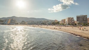 Una playa con un hotel al fondo.