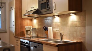 A modern kitchen with stainless steel appliances, wooden cabinets, and a tiled backsplash.