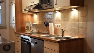 Eine moderne Küche mit Edelstahlgeräten, Holzschränken und einer gefliesten Spritzschutzwand.