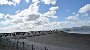 Ein Strand mit einer Umzäunung, Mülltonnen und blauem Himmel.