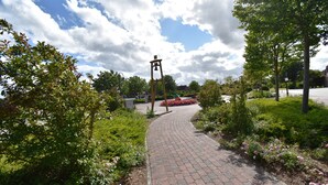 A paved pathway in a landscaped area with trees and flowers.