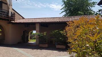 Un cortile con tetto in tegole, pavimento in pietra e piante in vaso.