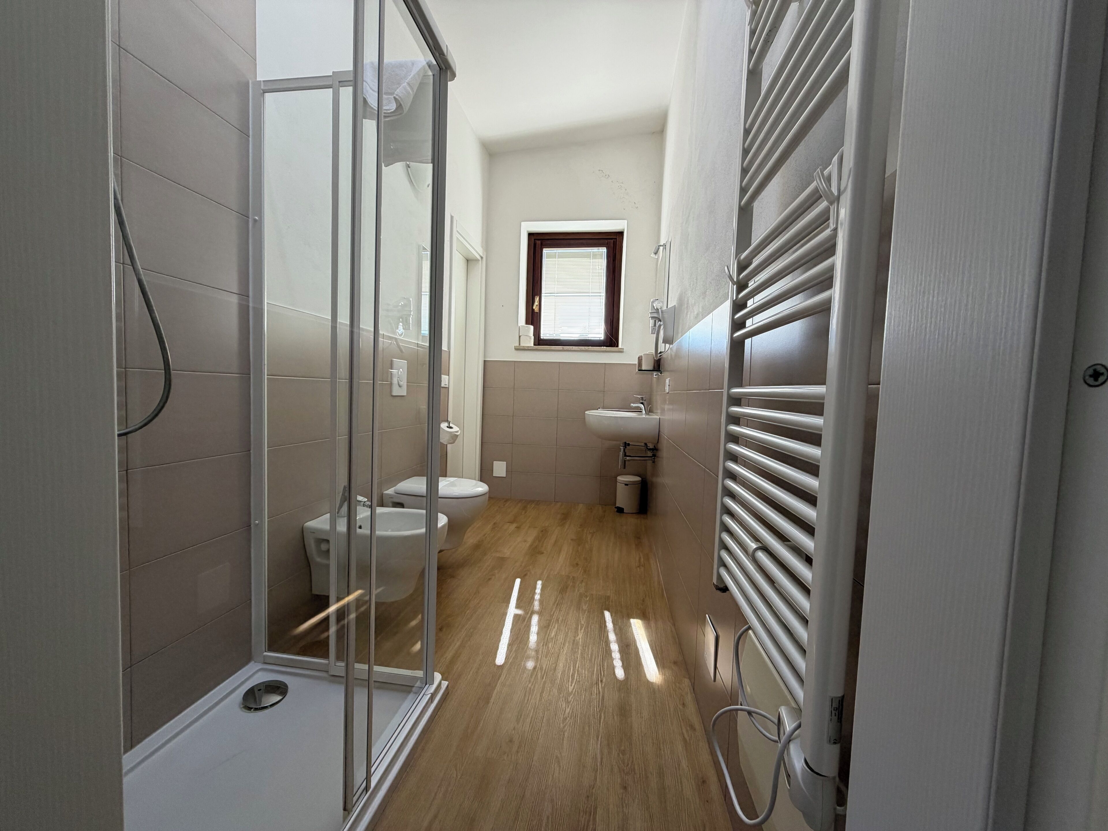 Une salle de bain moderne avec une douche à parois de verre, des toilettes, un lavabo et un porte-serviettes.