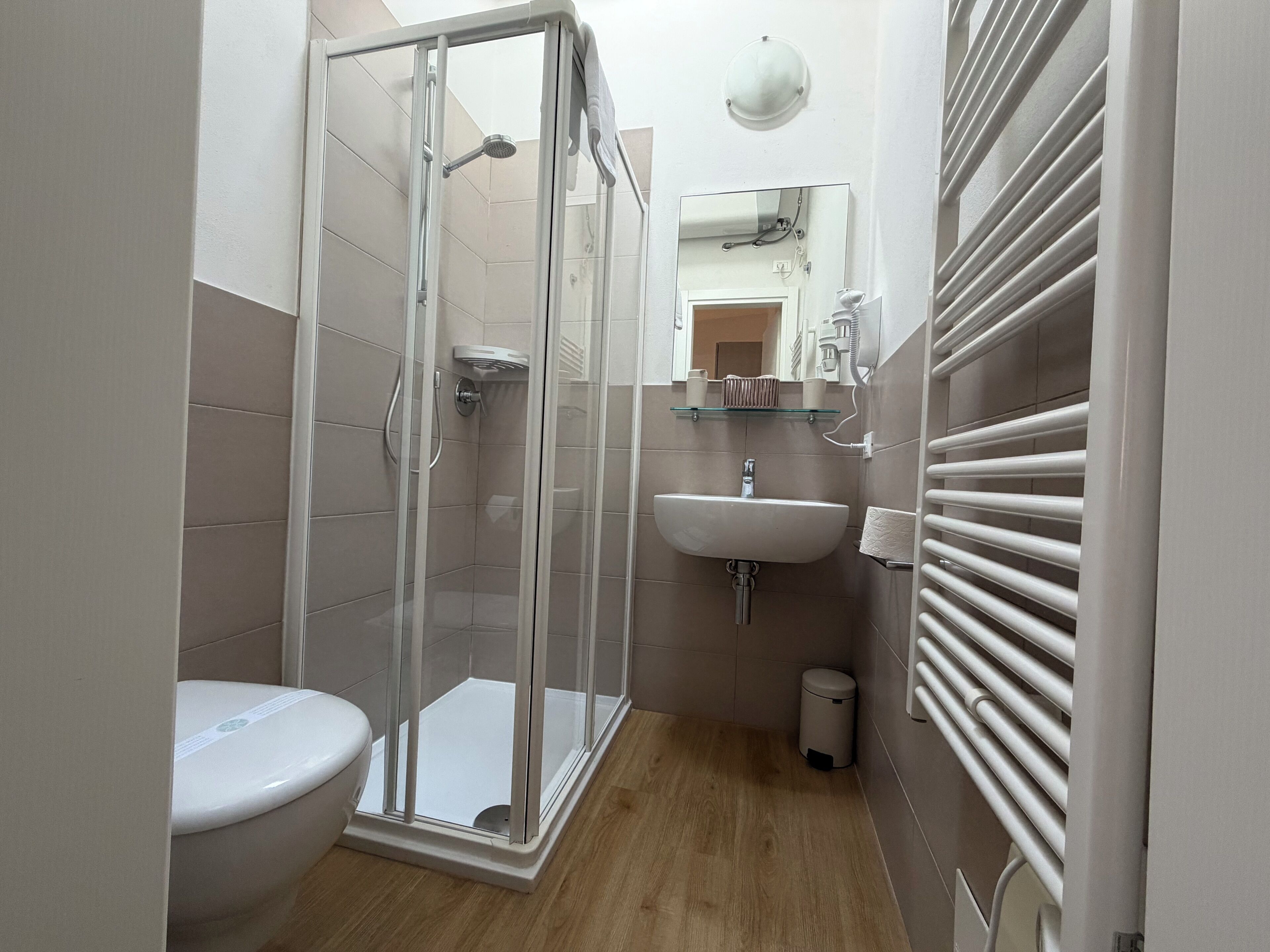 Ein modernes Badezimmer mit einer Duschkabine, einer Toilette, einem Waschbecken und einem Spiegel.
