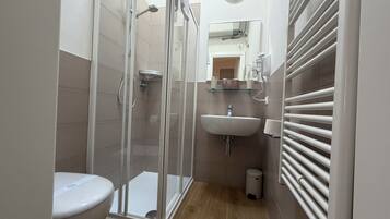 Ein modernes Badezimmer mit einer Duschkabine, einer Toilette, einem Waschbecken und einem Spiegel.