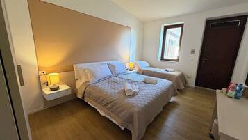Een slaapkamer met twee bedden, een nachtkastje met een lamp, een raam en een deur.