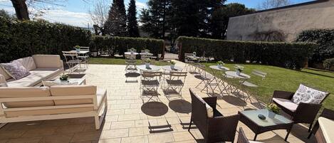 An outdoor patio with seating arrangements, tables, and potted plants.