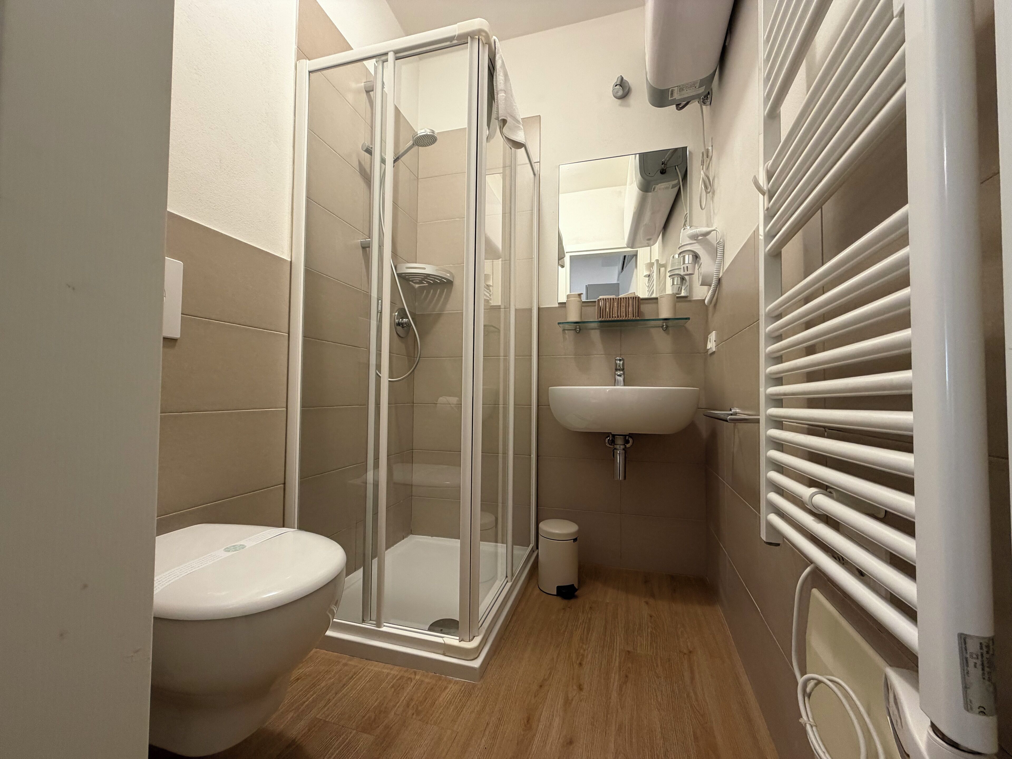 A bathroom with a glass-enclosed shower, a white sink, and a toilet.