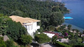 A coastal property with a white building, a blue-roofed structure, and a view of the sea and mountains. - Dimitra Apartments and Studios Gouvia (Corfu)