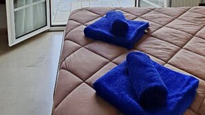 A bed with a brown quilted cover and two blue towels folded on it. - Dimitra Apartments and Studios Gouvia (Corfu)