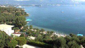 A coastal view with a clear sky, a boat in the water, and a mountain in the background. - Dimitra Apartments and Studios Gouvia (Corfu)