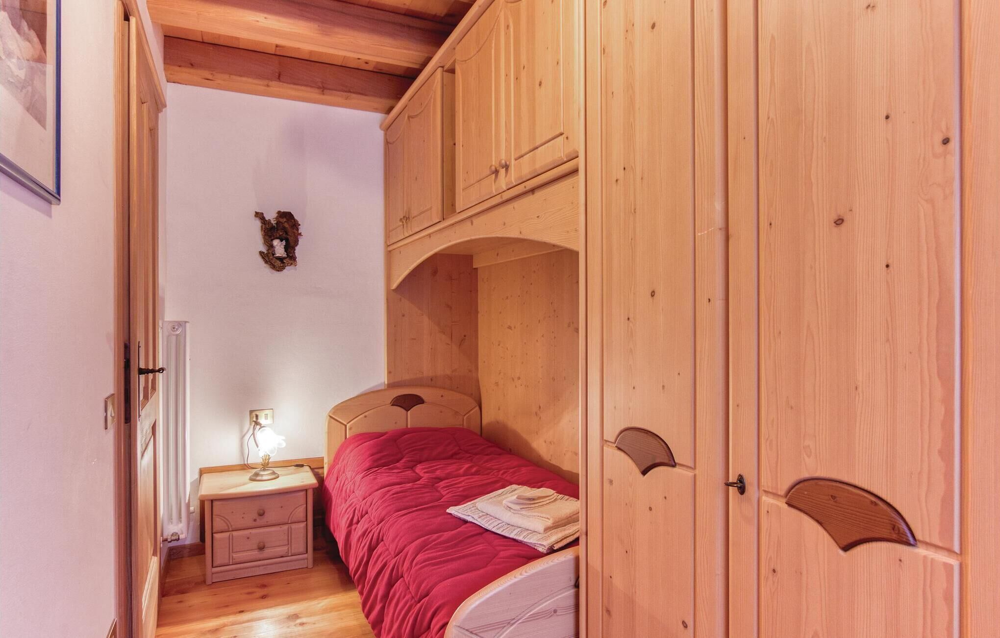 A wooden bedroom with a bed, a nightstand, and a wardrobe.