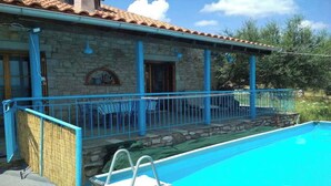 Una casa de piedra con un balcón azul y una piscina.