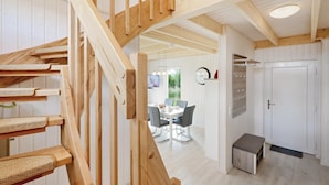 Una escalera de madera que lleva a un comedor con una mesa, sillas, un reloj y una puerta.