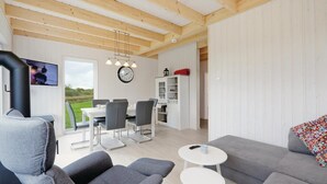 Una sala de estar moderna con un sofá gris, una mesa de centro blanca y un comedor con una mesa y sillas blancas.