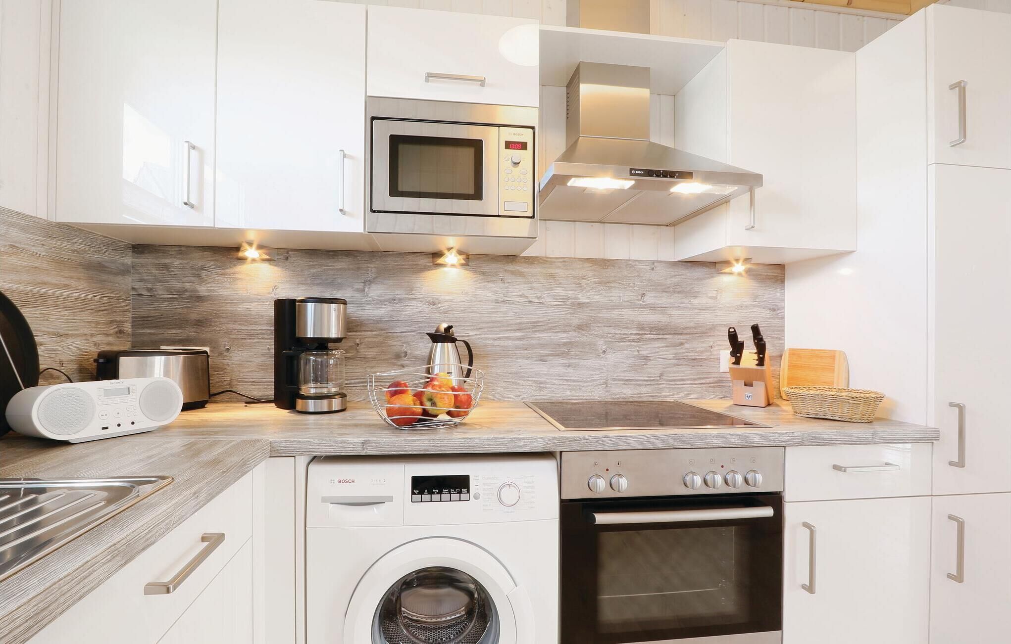 Cozinha moderna com armários brancos, máquina de lavar Bosch, lava-louças Bosch, micro-ondas e cafeteira.