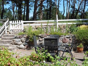 Une terrasse avec des marches en pierre, une clôture blanche en bois et du mobilier d’extérieur.